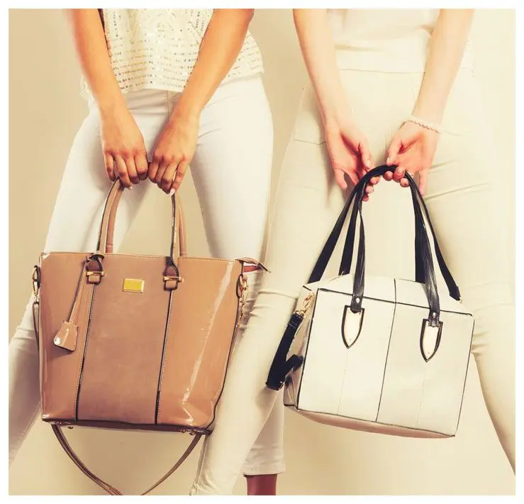 Two women holding onto a white purse