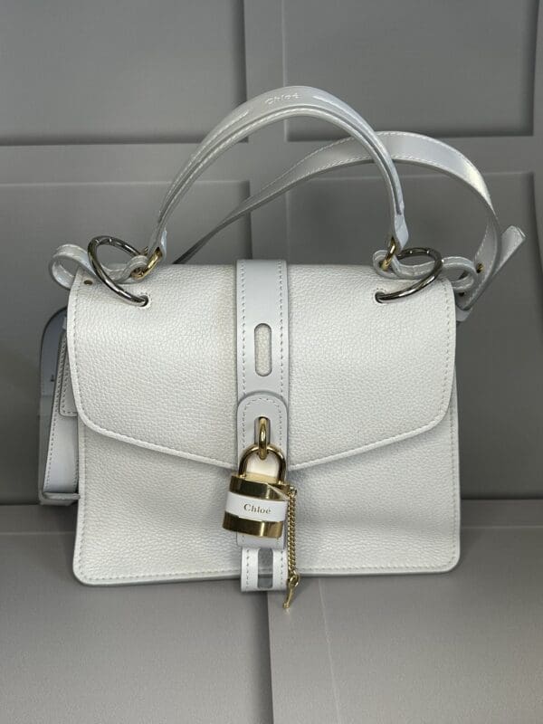 A white purse with a lock on the front.