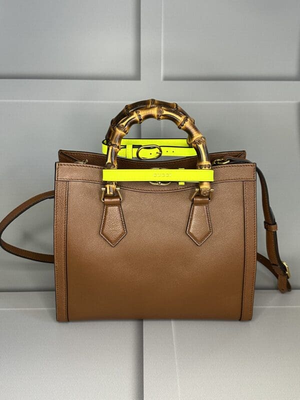 A brown purse with yellow accents on the handle.