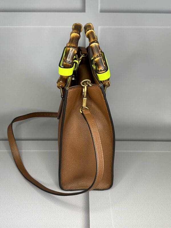 A brown purse with yellow straps and a handle.