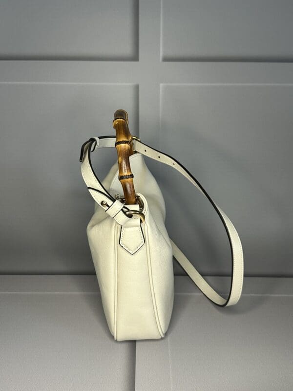 A white purse with bamboo handles on the handle.