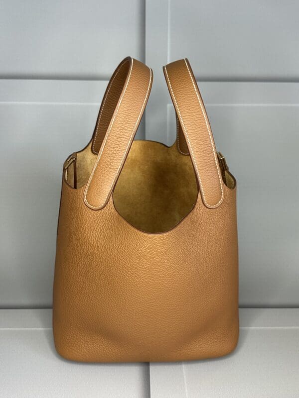 A tan leather bag sitting on top of a wall.