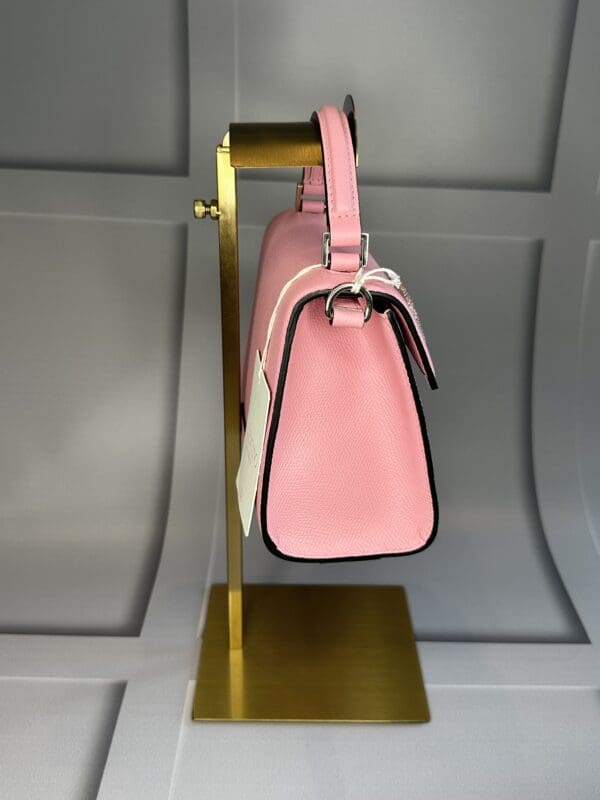 A pink purse hanging on a gold stand.